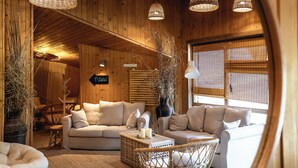 A cozy wooden interior with a sofa, wicker chairs, and a coffee table. - Green Village Resort (Sfantu Gheorghe)