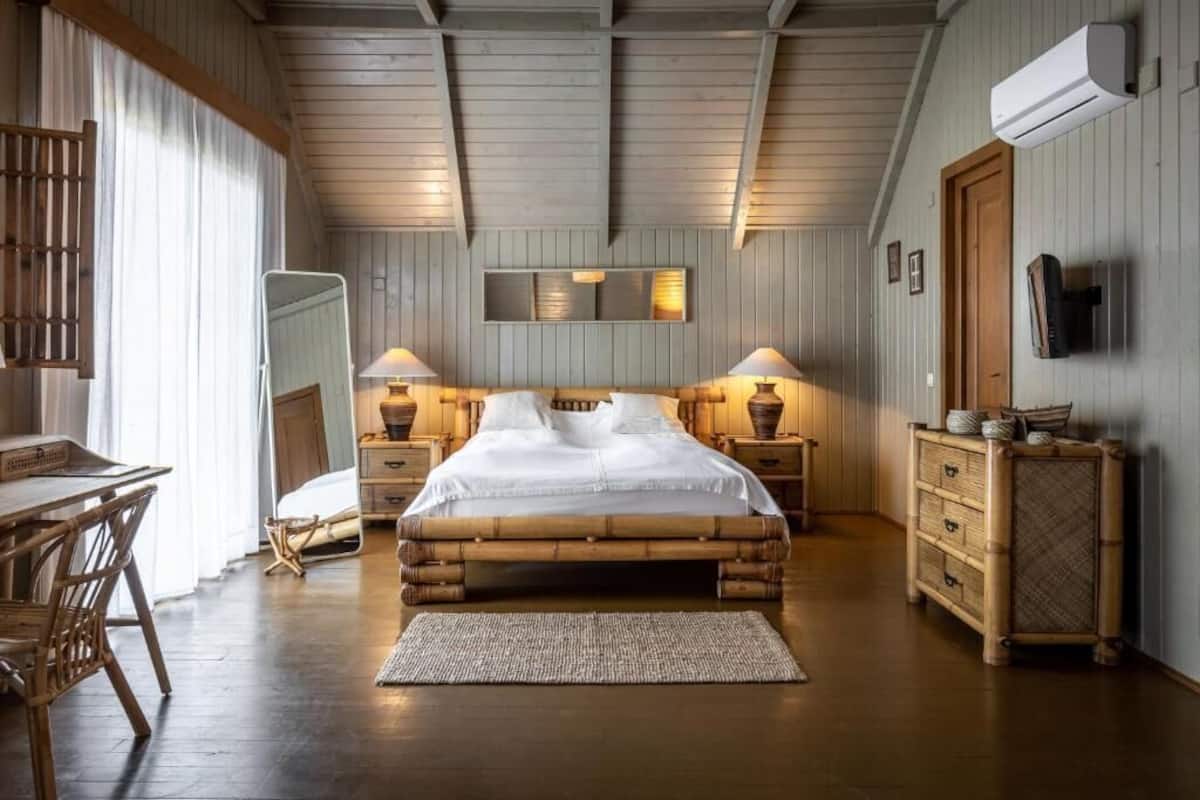 Ein gemütliches Schlafzimmer mit einem großen Bett, einem Holzkopfende, Nachttischlampen, einer hölzernen Kommode und einem Spiegel an der Wand.