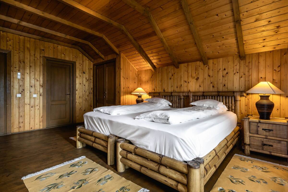 Ein Zimmer mit Holzboden, einem großen Bett, zwei Nachttischen und einer Tür.