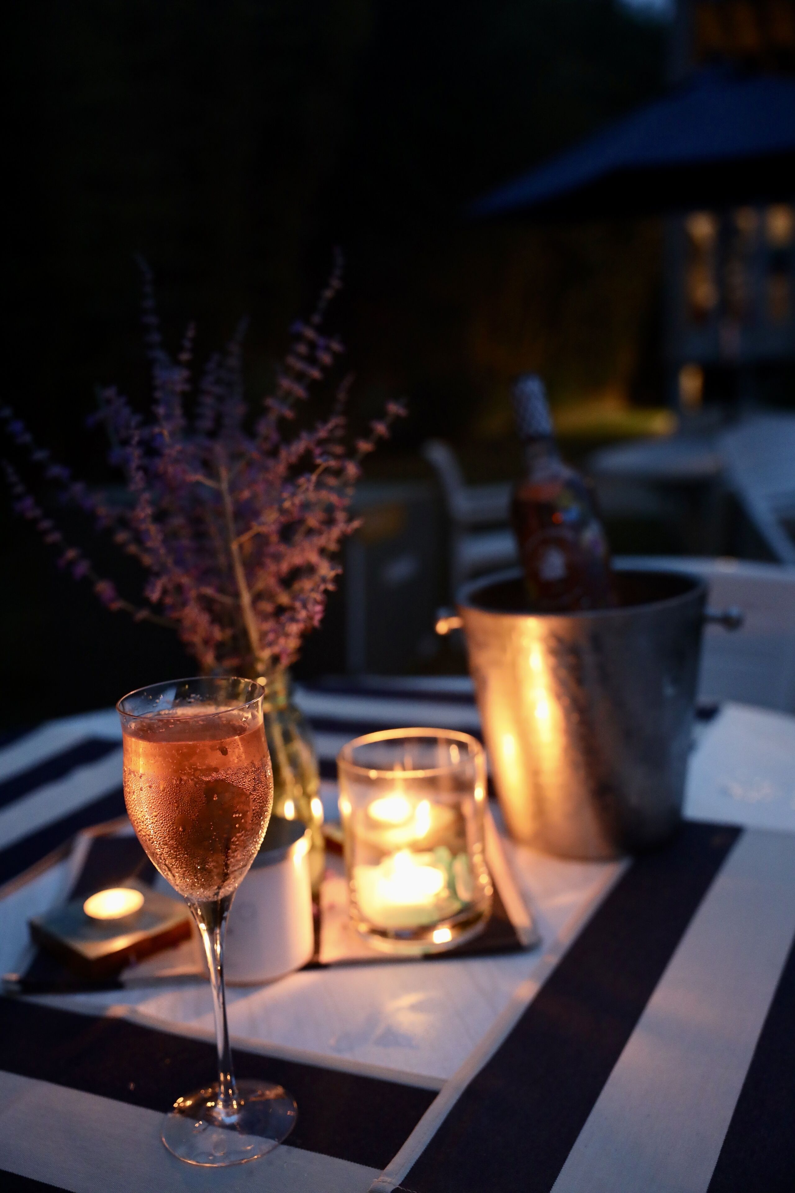 A table with a glass of champagne, a candle, and a bottle of champagne.