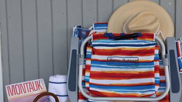 A beach chair with a striped towel, a straw bag, and a magazine titled 'MONTAUK'.