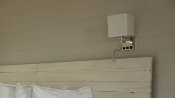 Un dormitorio con cabecera de madera, una mesita de noche redonda de madera y una colcha blanca.