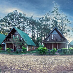 Dos cabañas con techos verdes, rodeadas de un bosque.
