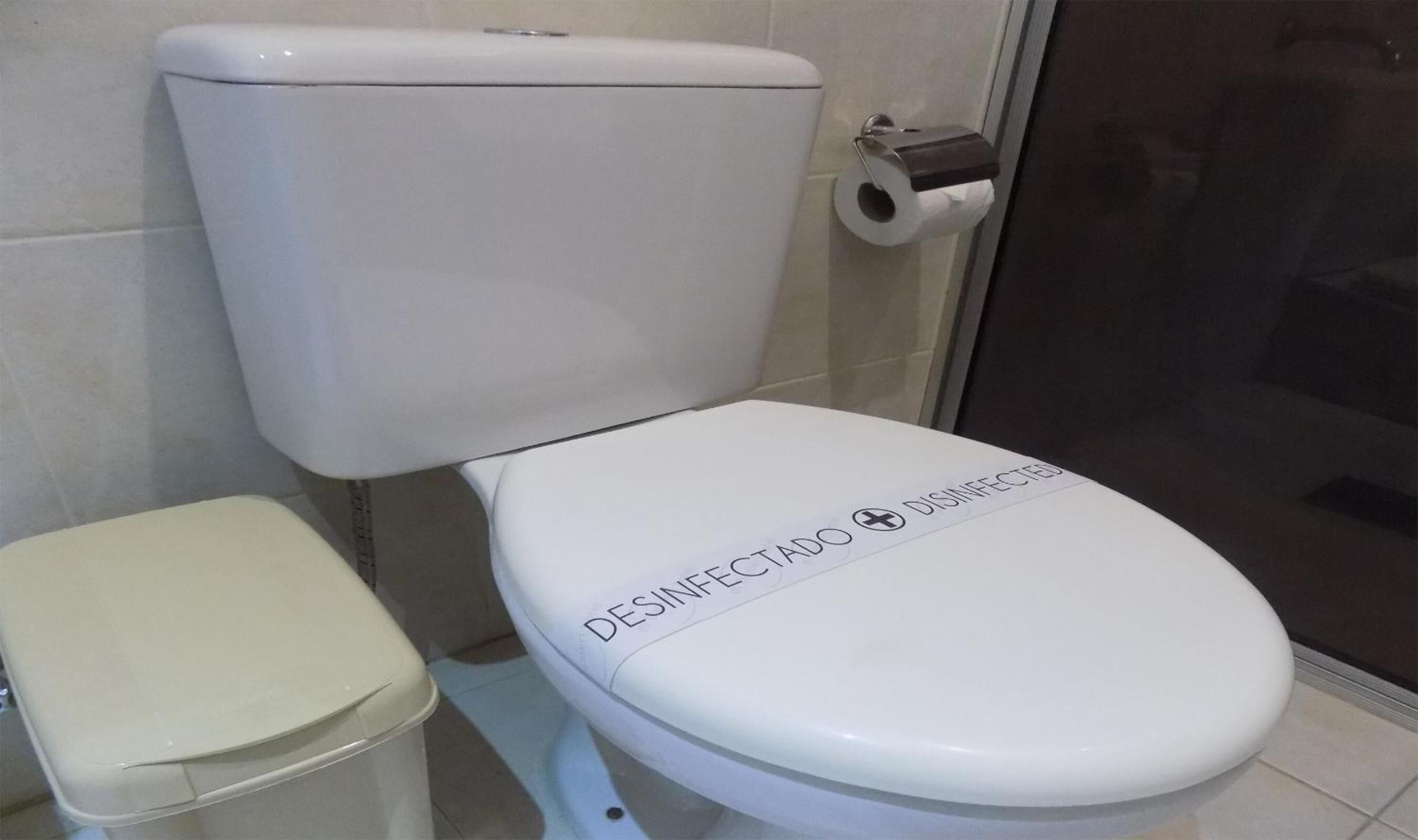Lavabo blanc amb una etiqueta que diu 'DESINFECTADO' i un suport de paper higiènic.