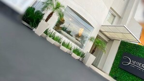 A modern building with a curved facade, multiple windows, and a green wall with a sign. - Danieri Asunción Hotel (Asunción)