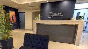 A reception desk with a sign reading "Danieri Agencia Hotel" and a dark blue upholstered chair in the foreground. - Danieri Asunción Hotel (Asunción)