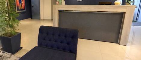 A reception desk with a sign reading "Danieri Agencia Hotel" and a dark blue upholstered chair in the foreground.