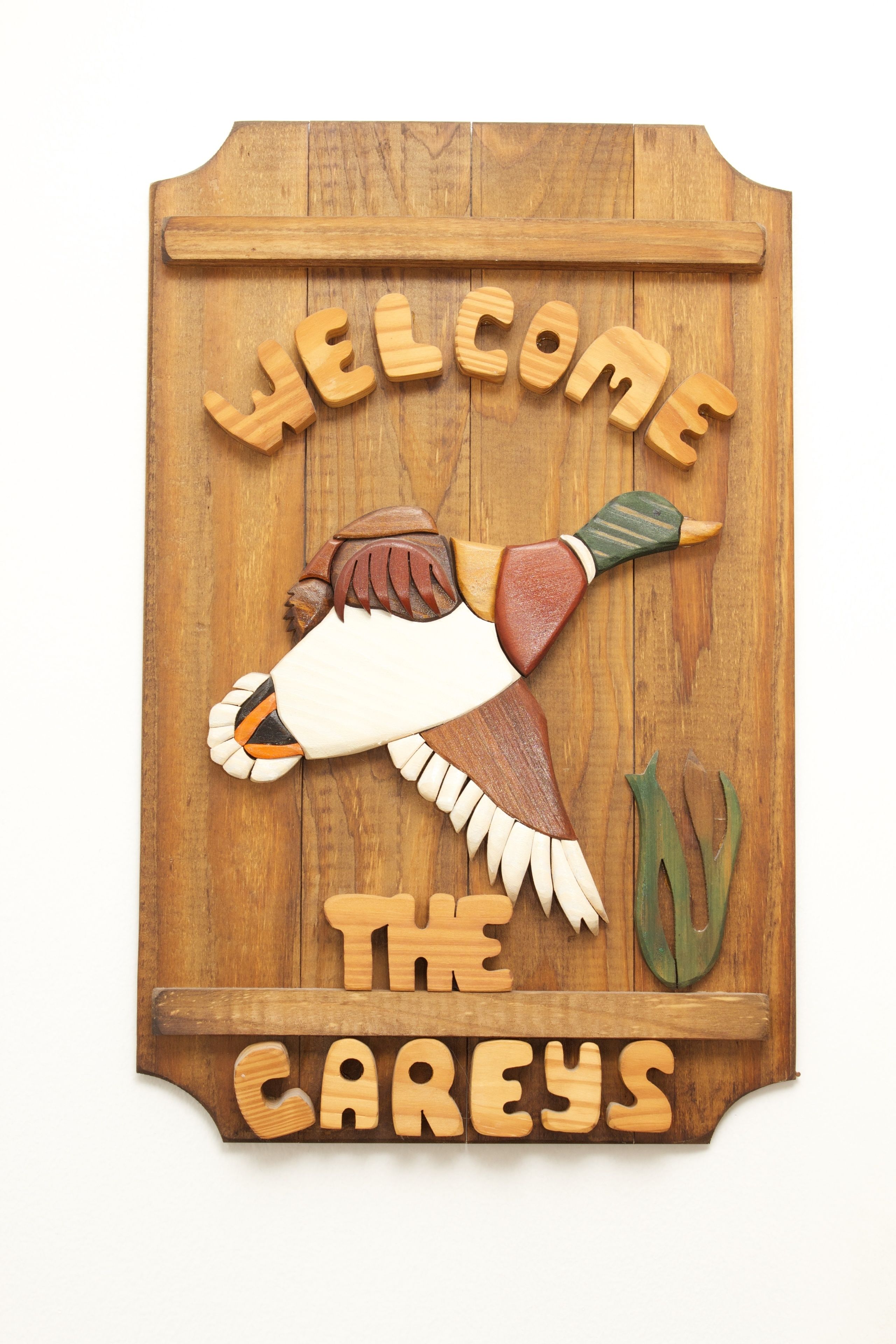 A wooden sign with carved figures and the text "WELCOME THE CAREYS".
