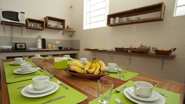Un comedor con una mesa de madera dispuesta para una comida, rodeada de individuales verdes, platos blancos y cubiertos.