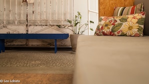Una habitación con un banco azul, una pared de madera, un sofá con cojines estampados y una planta en maceta.