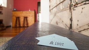 Una mesa de madera con un papel blanco encima, una pared roja y una zona de bar al fondo.