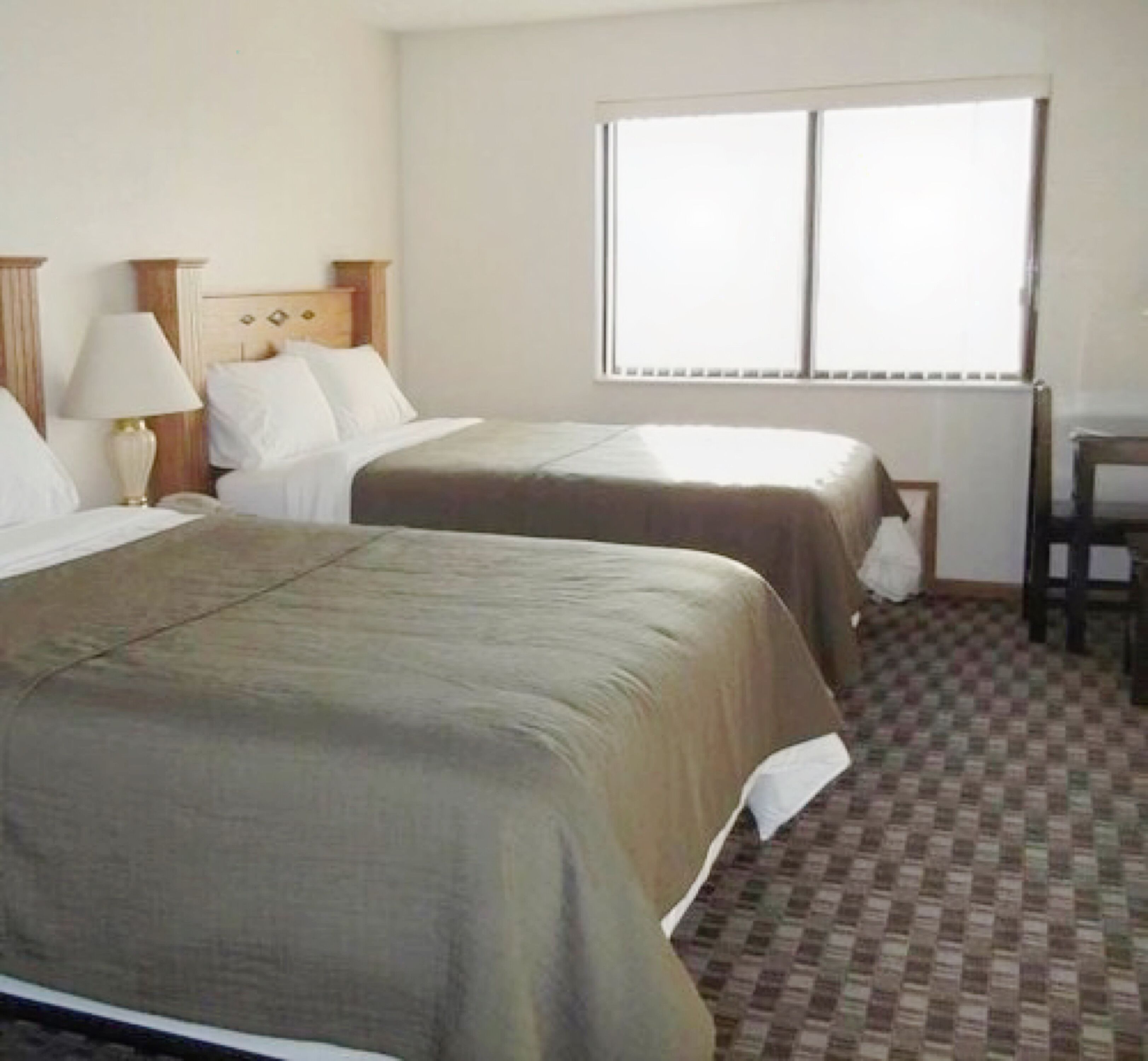 Een hotelkamer met twee bedden, een bureau en een raam.