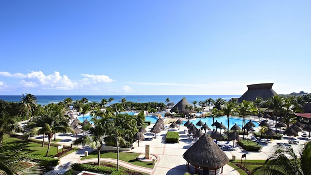 Ett semesterparadis med en stor pool, palmer och utsikt över havet.