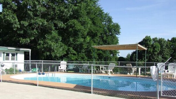 A swimming pool with a fenced area, lounge chairs, and a covered seating area. - The Skyline Motel (Osage Beach)