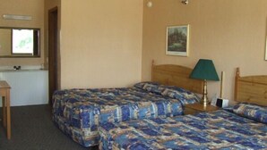 A hotel room with two beds, a desk, a chair, a lamp, and a painting on the wall. - The Skyline Motel (Osage Beach)