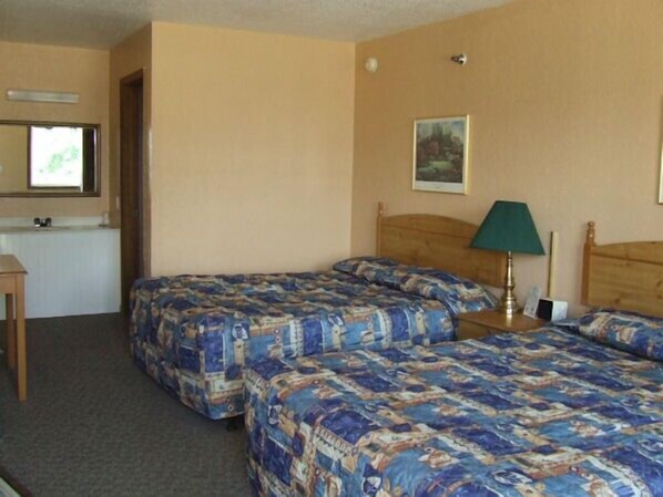 A hotel room with two beds, a desk, a chair, a lamp, and a painting on the wall. - The Skyline Motel (Osage Beach)