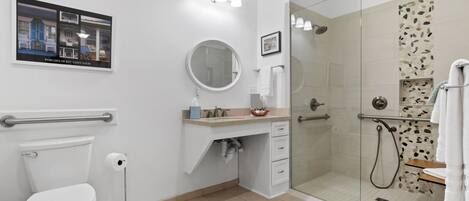 A modern bathroom with a toilet, sink, mirror, and glass-enclosed shower.