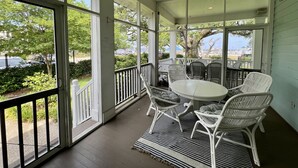 A covered porch with a table and chairs, large windows, and a view of the outdoors. - Bay Town Inn (Bay St Louis)