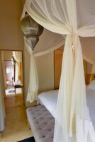 A bedroom with a bed, a bench, and a canopy.