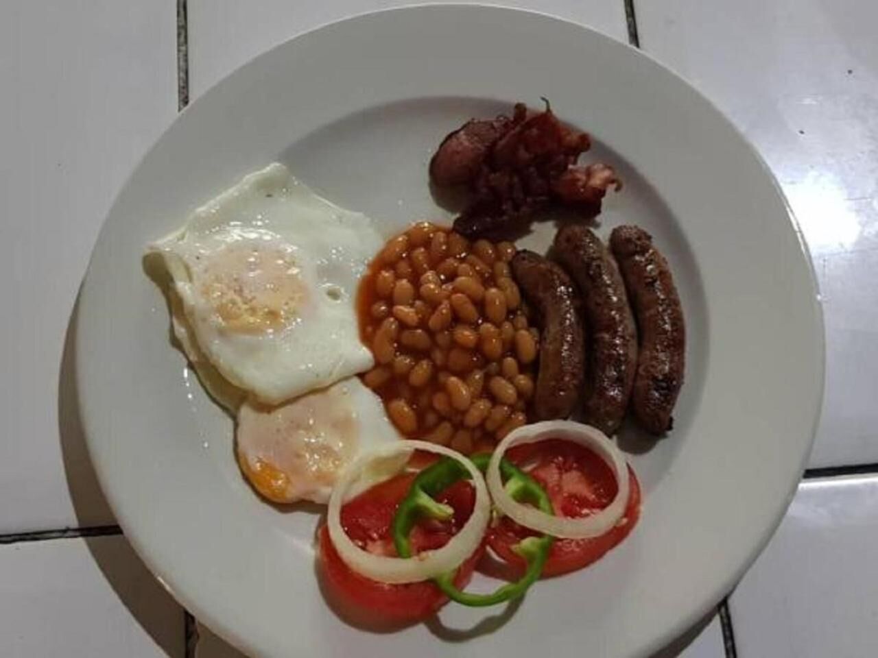 A plate with eggs, sausages, beans, and tomatoes.