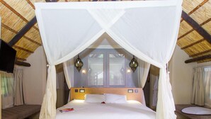 Una cama con dosel, lámparas de noche y vista al exterior por una ventana.