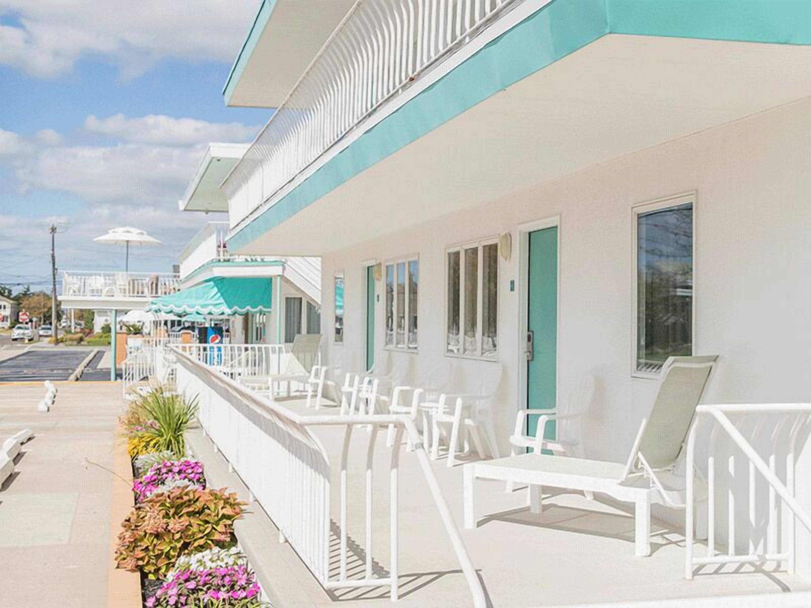 Un hôtel situé en bord de mer, doté d’un balcon, de chaises longues blanches et d’un parasol à l’effigie de Pepsi.