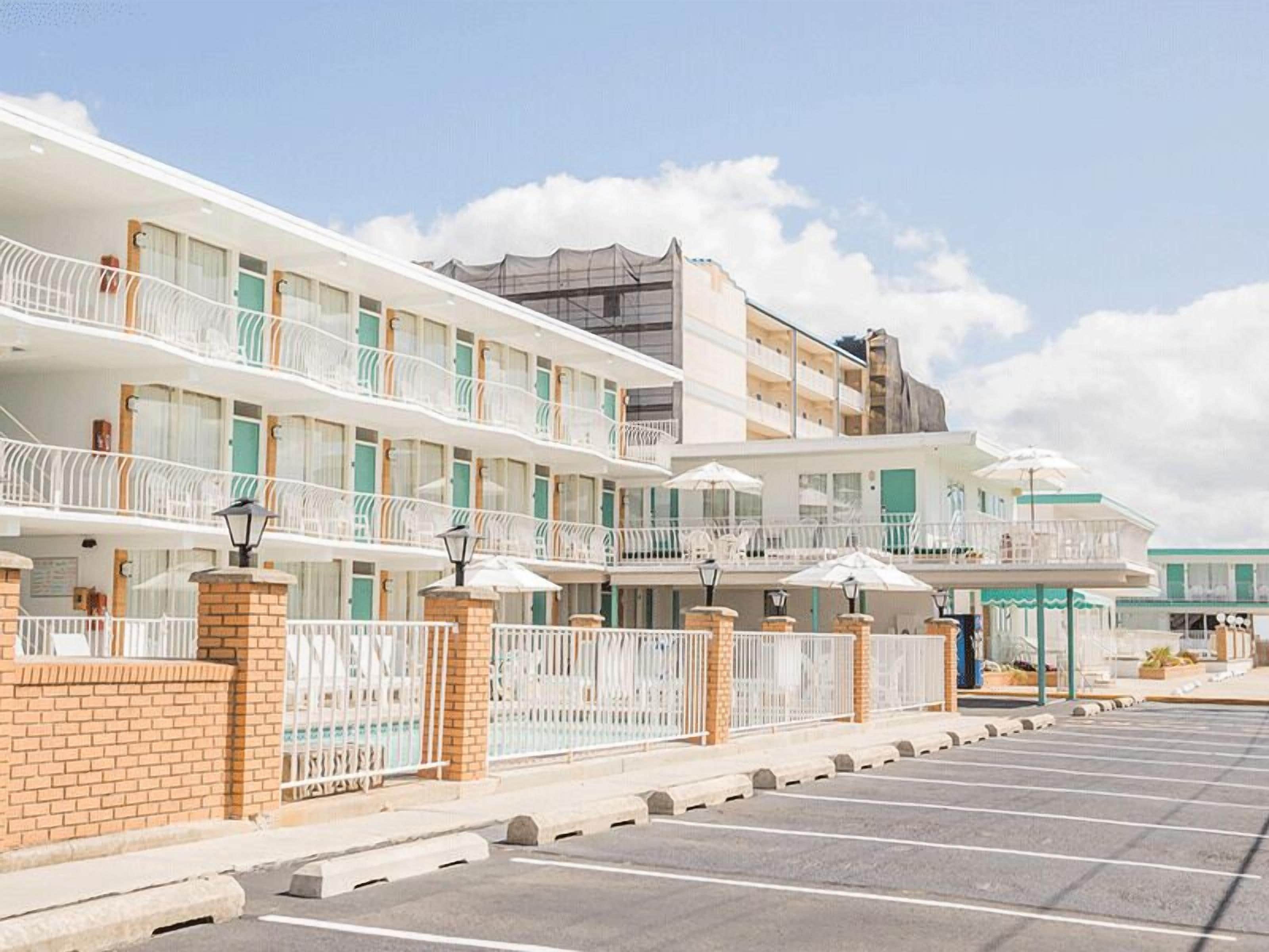 Um hotel com vários andares, varandas, estacionamento e área externa coberta para estar.