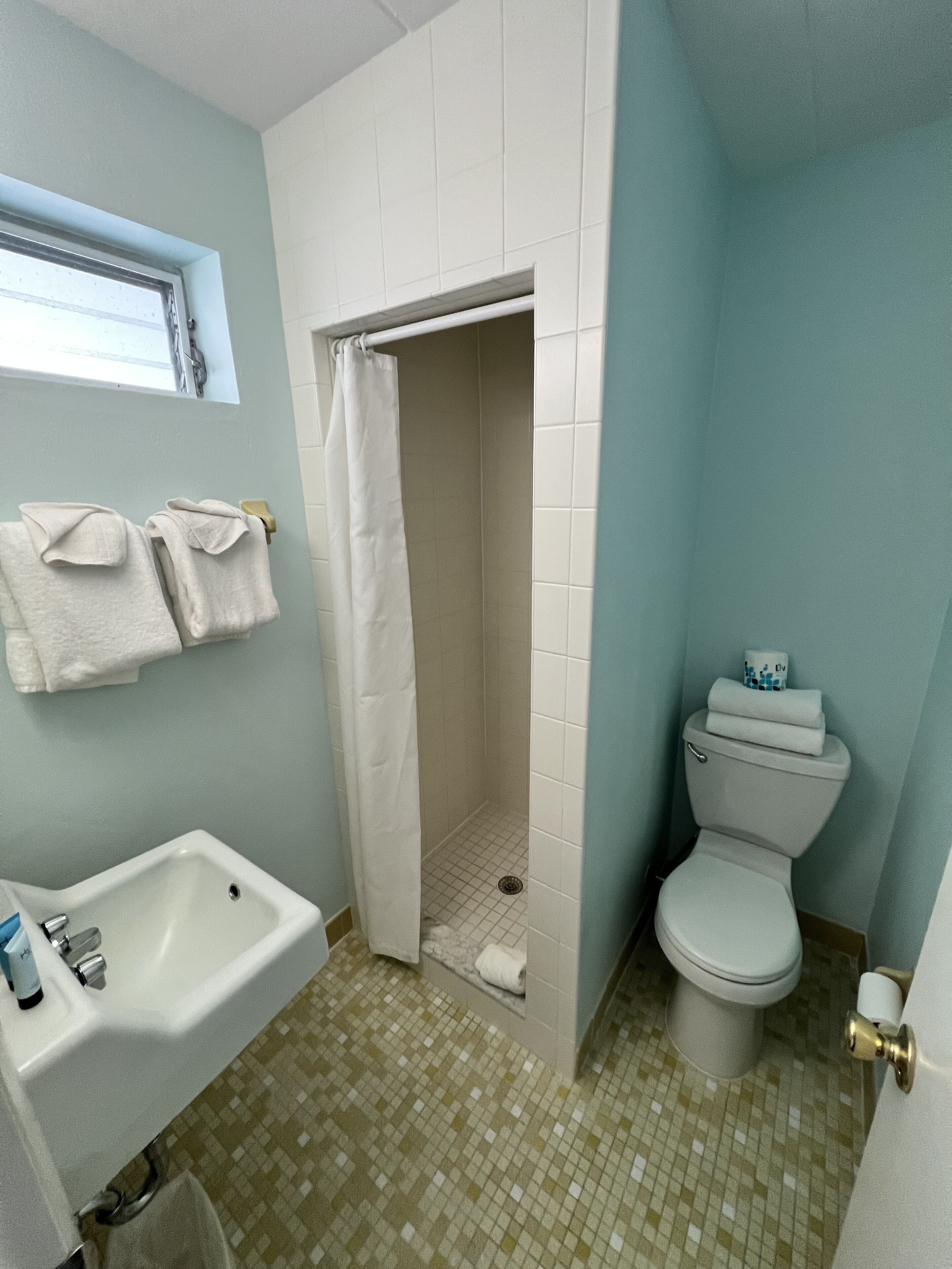 Een badkamer met douche, toilet en wastafel.