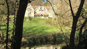 Une grande maison de style traditionnel, dotée d’une pelouse bien entretenue et d’un étang en premier plan.