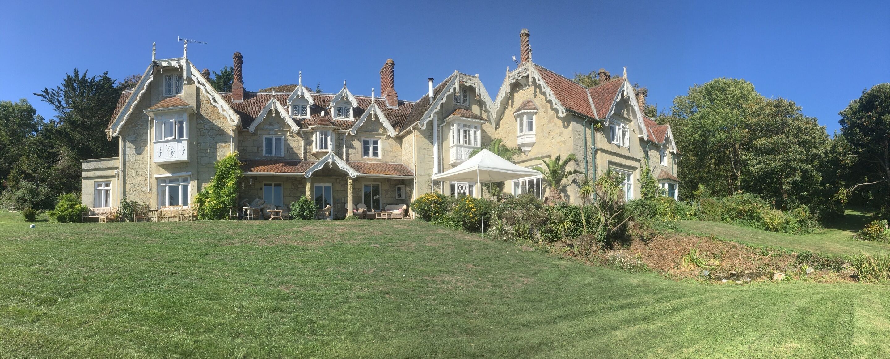 A large, historic house with multiple gabled roofs and a well-maintained lawn.