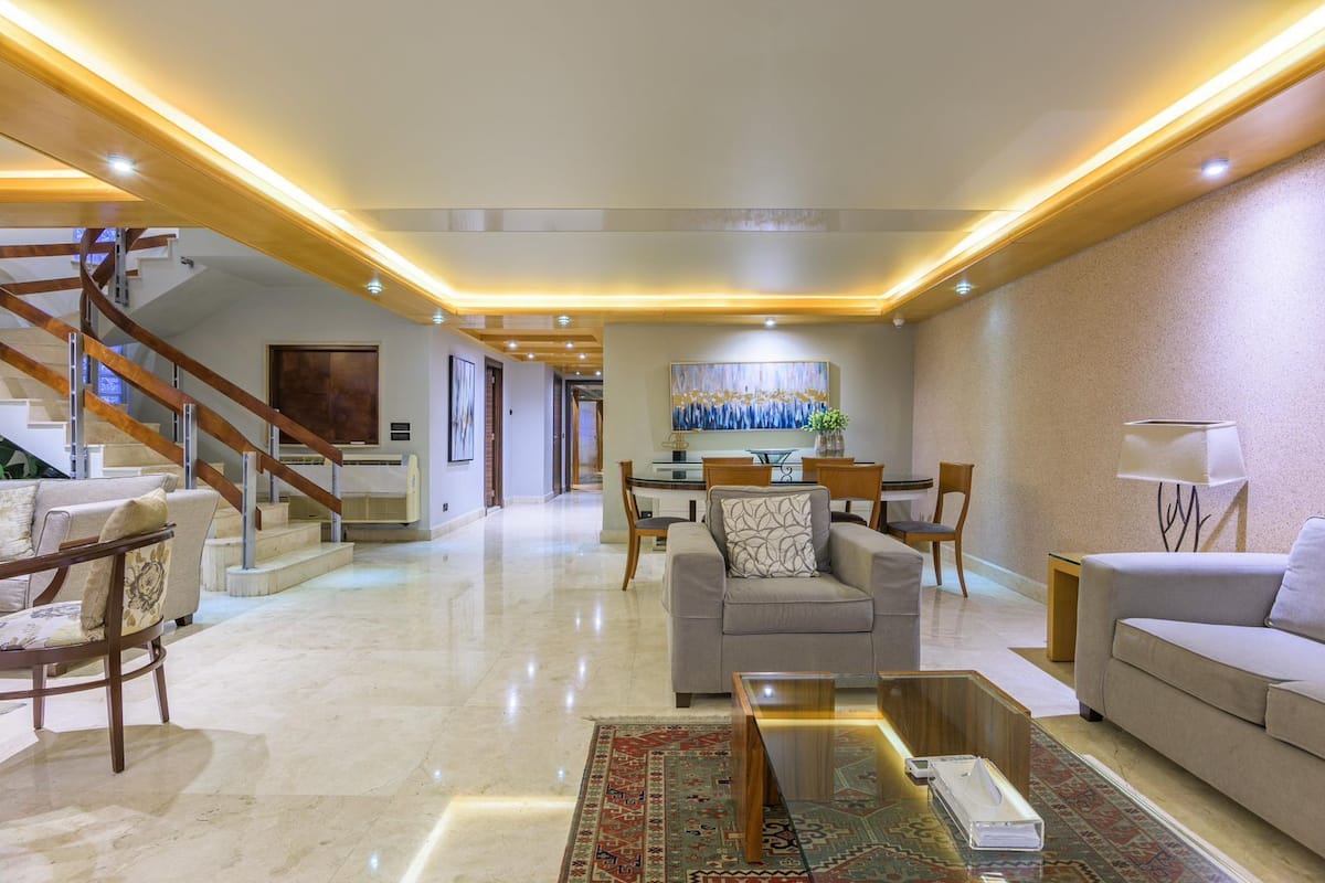 A spacious living area with a staircase, a dining area, and a sofa set.