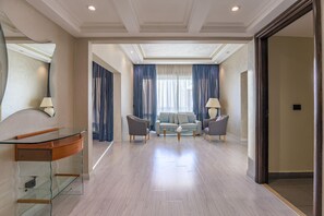 A modern living room with a glass coffee table, two grey armchairs, a sofa, and a large mirror. - Lahoya Homes (Beirut)