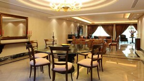 A spacious dining area with a round table and chairs, a chandelier, and a large mirror on the wall. - Lahoya Homes (Beirut)