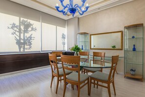 A dining area with a glass table surrounded by wooden chairs, a blue chandelier, and a large mirror on the wall. - Lahoya Homes (Beirut)