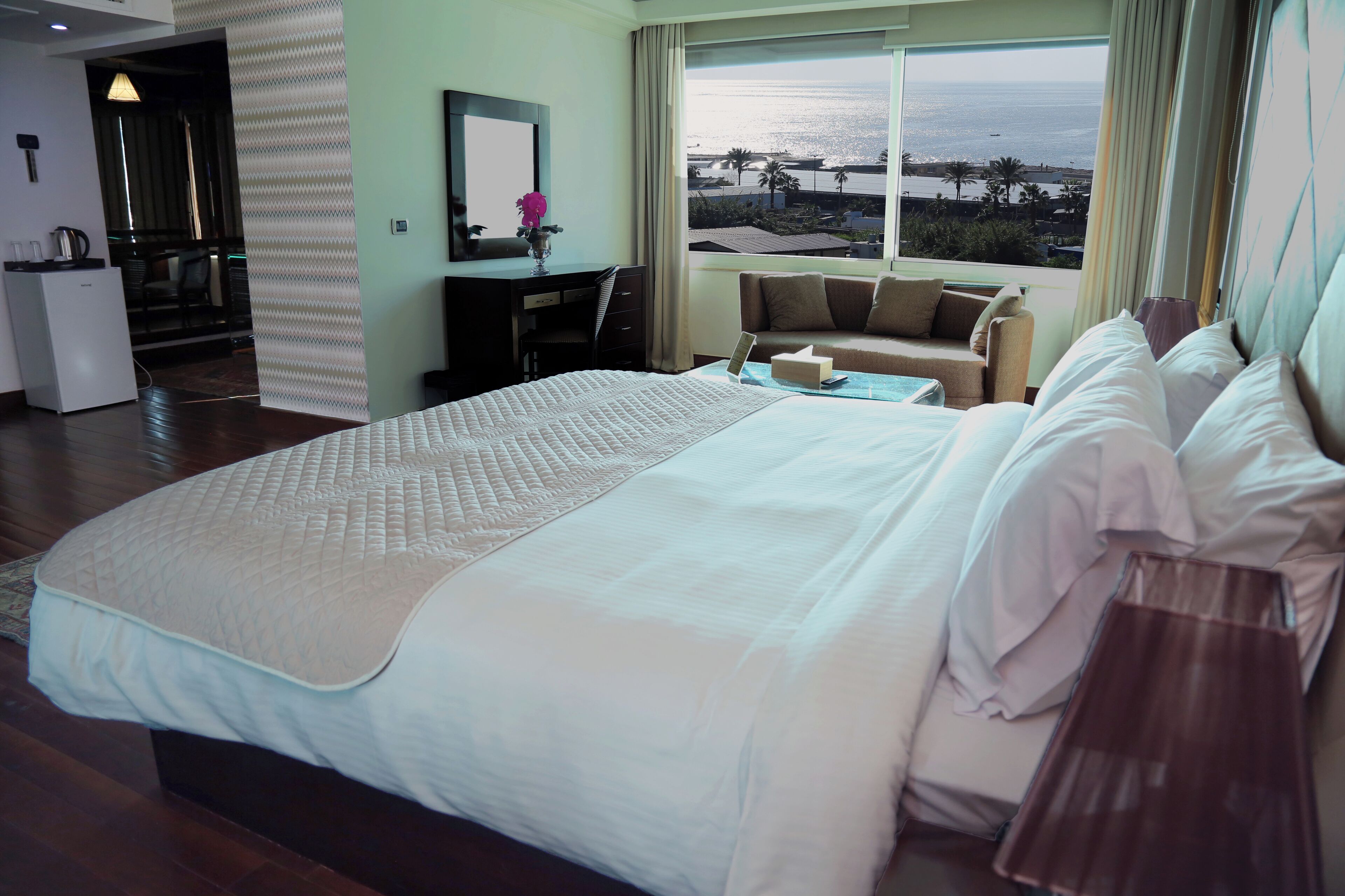 Habitación de hotel con una cama grande, un escritorio, una silla y vista al océano.