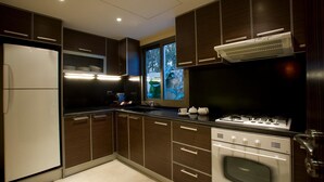 A modern kitchen with dark wood cabinets, a built-in oven, a gas stove, and a refrigerator. -  Lahoya Beirut (Beirut)