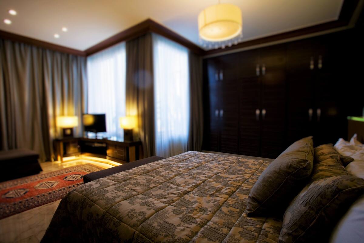 A hotel room with a large bed, a desk, a chair, and a television.