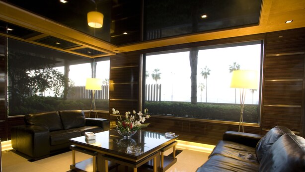 A modern living room with a glass coffee table, leather sofas, and large windows with a view of palm trees. -  Lahoya Beirut (Beirut)