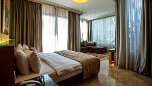A spacious hotel room with a large bed, a seating area, and a view of the city. -  Lahoya Beirut (Beirut)