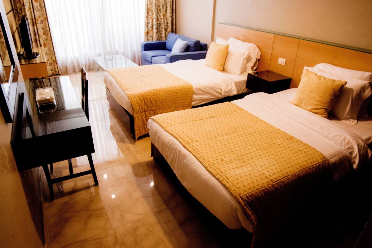 A hotel room with two beds, a desk, and a chair.