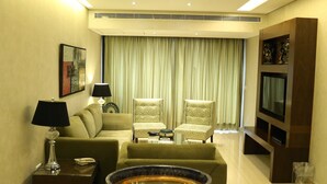 A modern living room with a sofa, armchairs, a coffee table, and a TV mounted on the wall. - Verdun Suites Hotel (Beirut)
