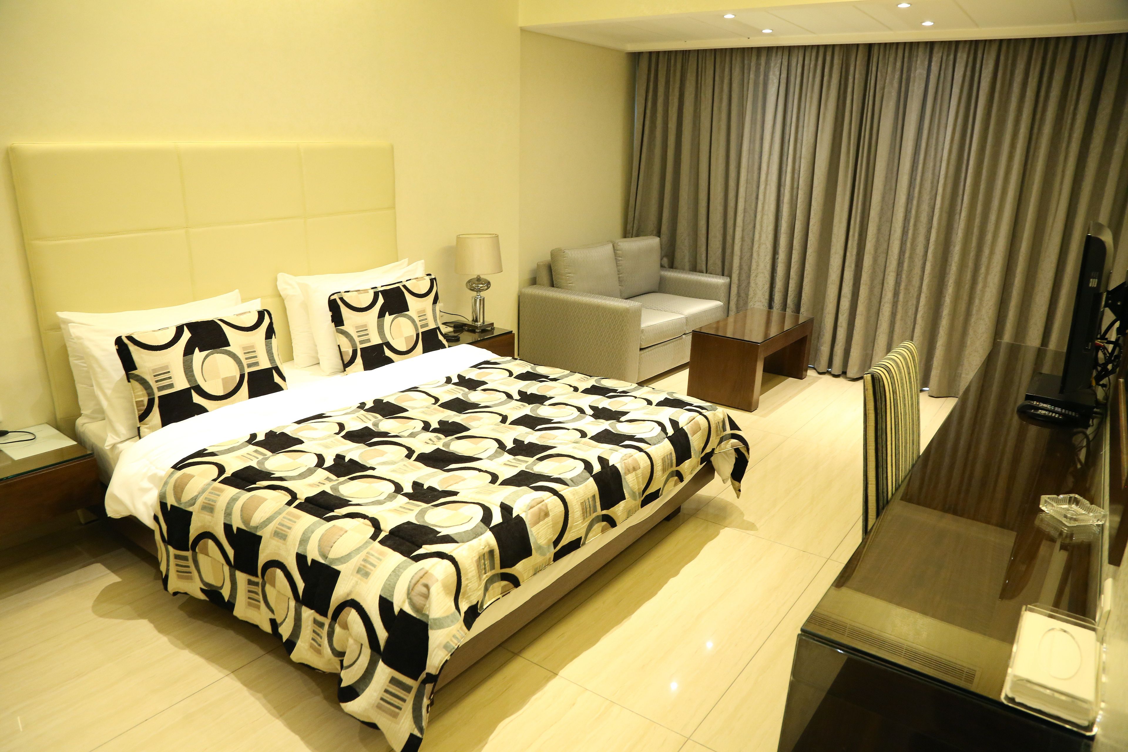A hotel room with a bed, a sofa, a desk, and a TV.