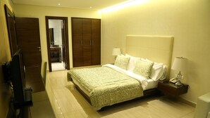 A hotel room with a bed, bedside table, lamp, and a wardrobe. - Verdun Suites Hotel (Beirut)