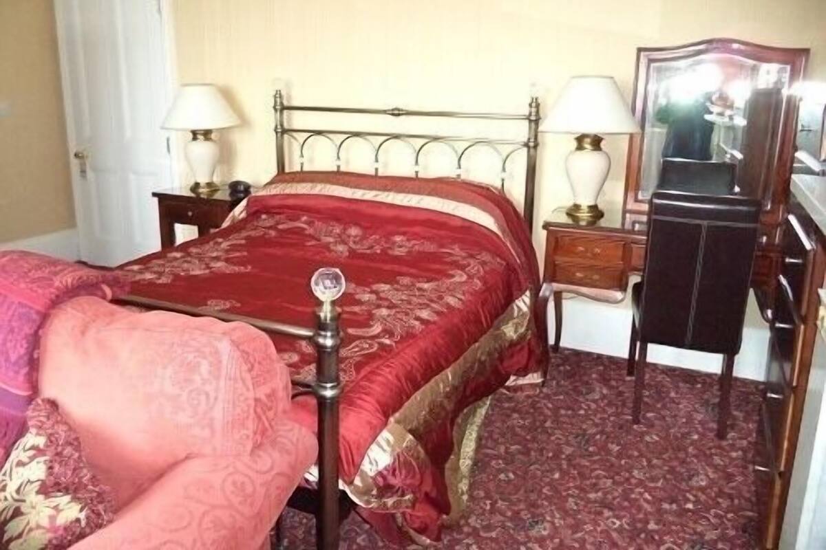 A room with a bed, two bedside tables with lamps, a mirror, and a door.