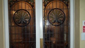 Une porte blanche dotée de deux panneaux de verre ornés de motifs métalliques décoratifs.
