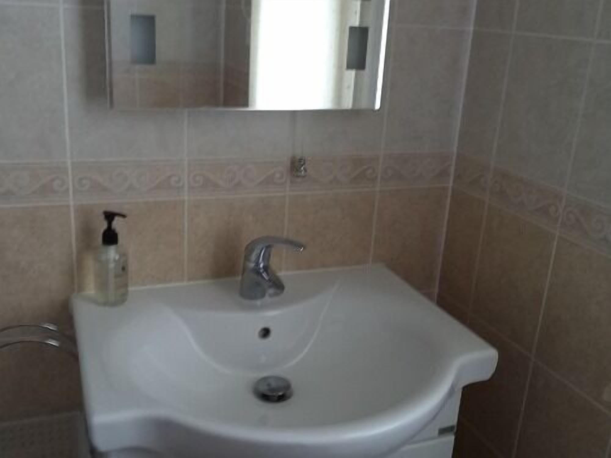 A bathroom sink with a mirror above it, a soap dispenser, and a faucet.