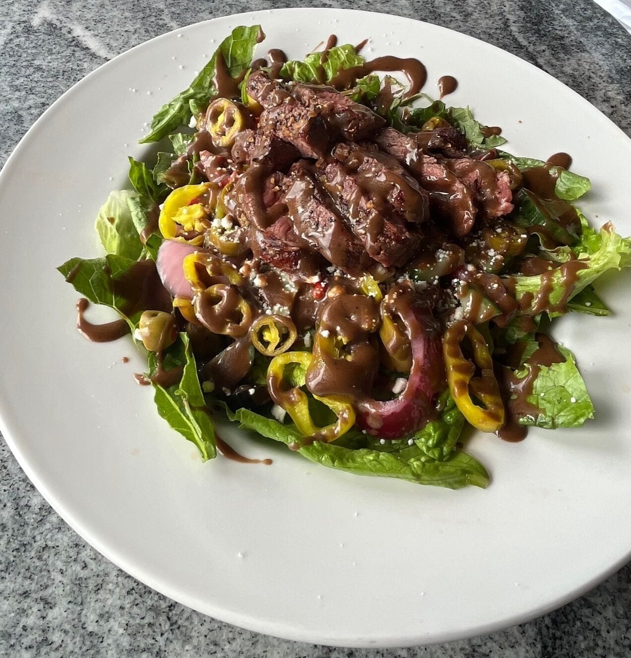 A plate of food with meat, vegetables, and a brown sauce.