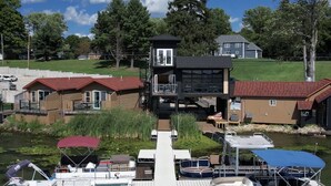 A lakeside property with a dock, boats, and a house with a red roof. - Edinboro Lake Resort Cabins (Edinboro)