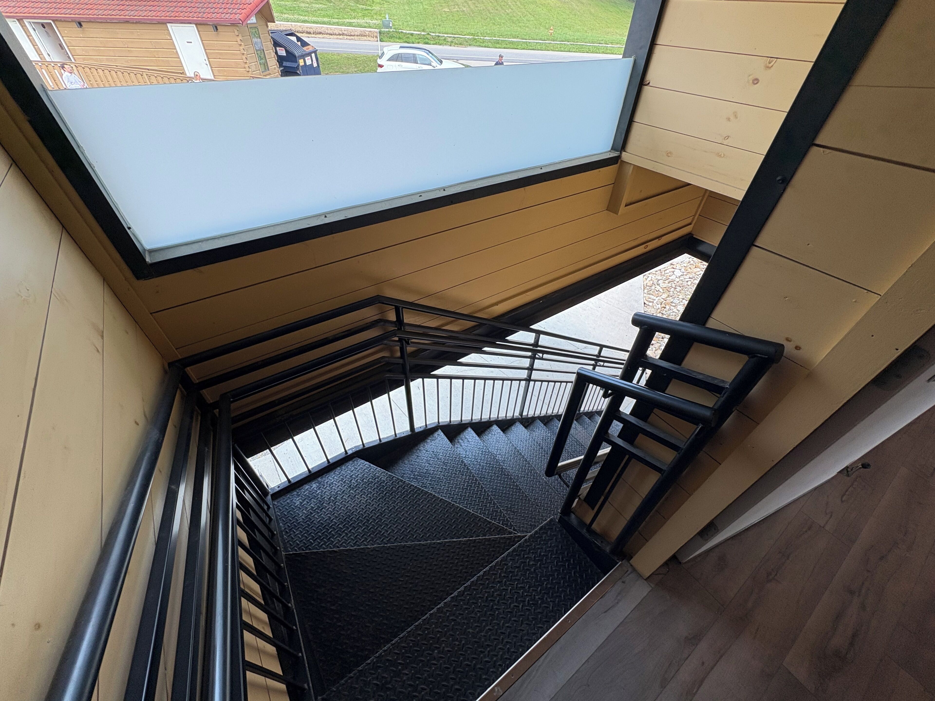 A staircase with a metal railing, a blue ceiling, and a view of the outside.
