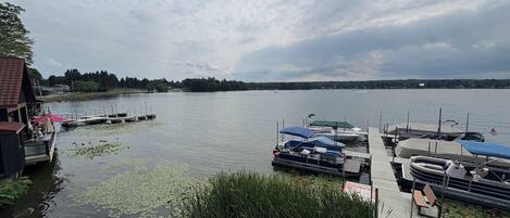 Une jetée au bord du lac avec des bateaux, une plateforme en bois et un bâtiment doté d’une terrasse.